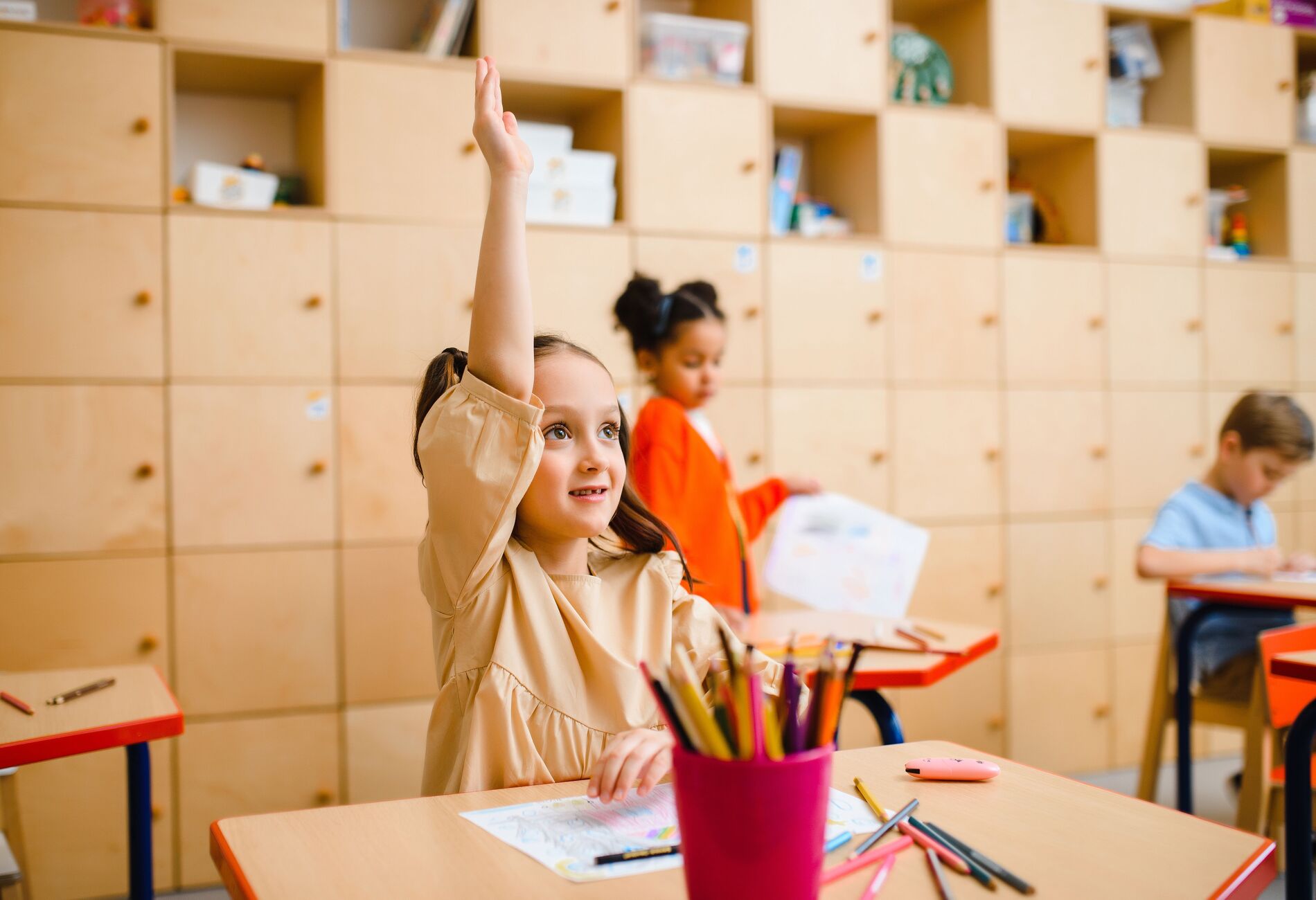 Een meisje steekt vol vertrouwen haar vinger op in de klas